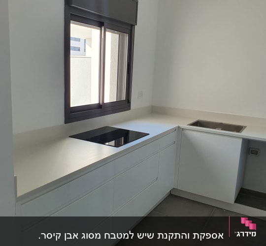 מטבח עם משטח שיש לבן וכיריים שחורות
